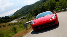 Красный Ferrari 458 Italia наслаждается поездкой за городом в солнечный день